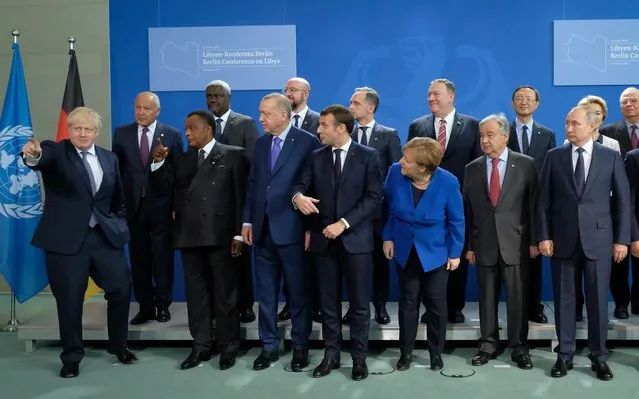 British Prime Minister Boris Johnson (L) gestures as other participants, including German Chancellor Angela Merkel, French President Emmanuel Macron, Russian President Vladimir Putin, U.S. Secretary of State Mike Pompeo and Turkish President Recep Tayyip Erdogan, look before a group photo at an international summit on securing peace in Libya at the Chancellery on January 19, 2020 in Berlin, Germany. Leaders of nations and organizations linked to the current conflict are meeting to discuss measures towards reaching a consensus between the warring sides and ending hostilities. (Photo by Sean Gallup/Getty Images)