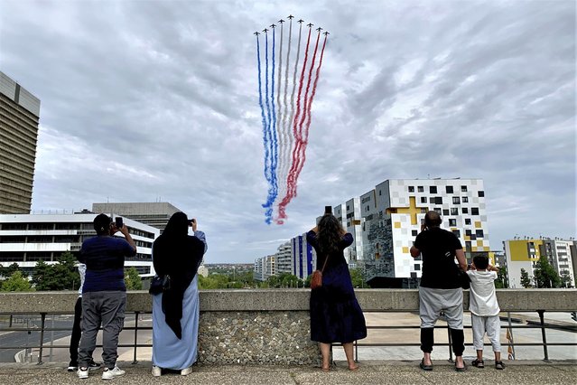 Residents watch jets from the Patrouille de France flying over Paris suburb Nanterre during the Bastille Day military parade Friday, July 14, 2023 in Nanterre. France celebrated its national holiday with whizzing warplanes and a grand Bastille Day parade in Paris – and with more than 100,000 police deployed around the country to prevent a new outbreak of unrest in underprivileged neighborhoods. (Photo by Youcef Bounab/AP Photo)