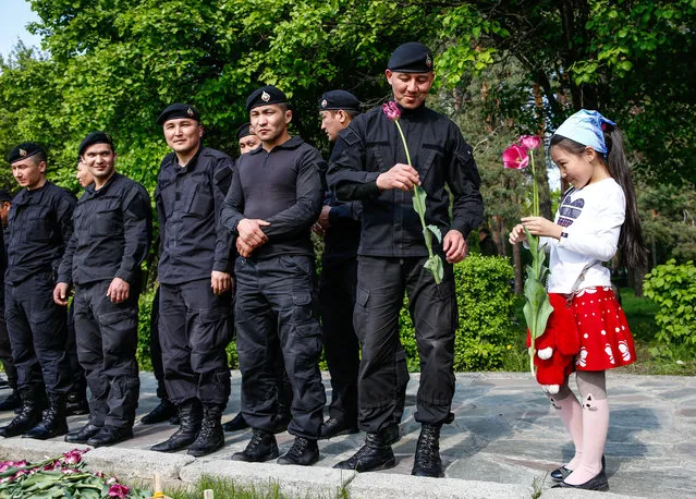 A girl gives a flower to a police officer during a protest in Almaty on the Day of Unity of the People of Kazakhstan in Almaty on May 1, 2019. (Photo by Pyotr Trotsenko/Radio Free Europe/Radio Liberty)