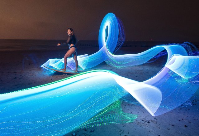 Jess Ashley poses with a surfboard on the beach at Frinton-on-Sea on Essex, UK as coloured LED lights are moved to create a light painting during a 11-second exposure on September 27, 2024. (Photo by Kevin Jay/Picture Exclusive)