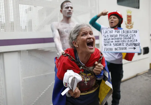 A woman screams in front a metal screen barrier set by National Police to block a university students' protest calling on the military to abandon President Nicolas Maduro and join their fight to end the nation's historic crisis in Caracas, Venezuela, Thursday, November 21, 2019. (Photo by Ariana Cubillos/AP Photo)