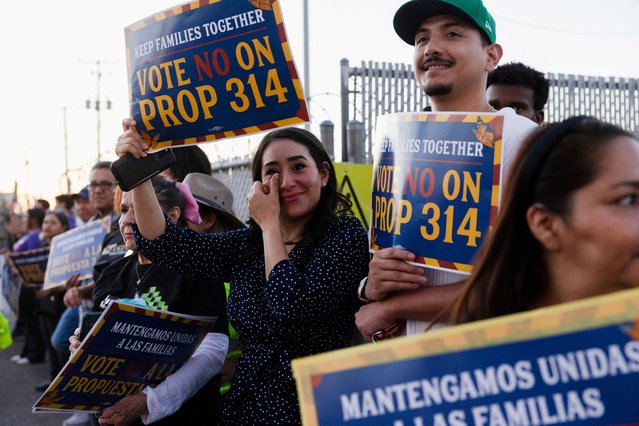 People gather with posters outside a ballot drop-off location during a rally against Proposition 314 organised by immigrant rights activists, in Phoenix, Arizona on October 21, 2024. (Photo by Zoe Meyers/Reuters)