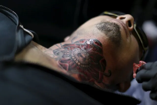 A man rests while getting a tattoo on his neck during the annual Panama City Ink Fest in Panama City August 16, 2015. (Photo by Carlos Jasso/Reuters)
