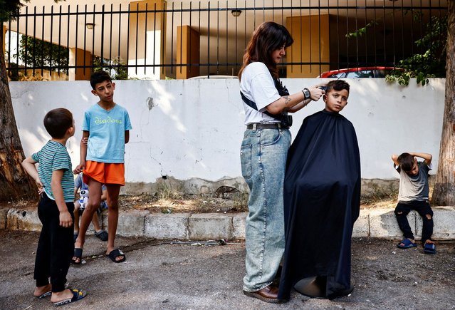 Kristie Rahal, 28, a Lebanese hairdresser who has been volunteering to give free haircuts to displaced children twice a week since the first week of October, cuts a child's hair outside a school used as a temporary shelter, in Baabda, Lebanon on October 31, 2024. (Photo by Yara Nardi/Reuters)