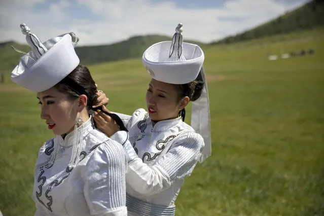 A Mongolian performer helps another with her hair before a shortened version of a Naadam festival, a traditional Mongolian cultural and sporting event, held during the 11th Asia-Europe Meeting (ASEM) in Ulaanbaatar, Mongolia, Friday, July 15, 2016. (Photo by Mark Schiefelbein/AP Photo)