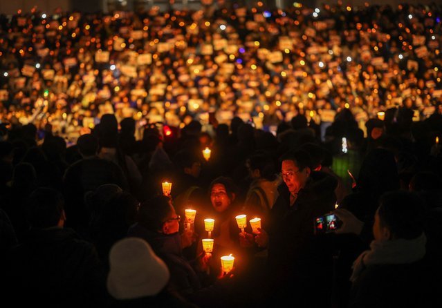 People hold candles and signs during a candlelight vigil to demand the resignation of South Korean President Yoon Suk Yeol, who declared martial law which was reversed hours later, at the National Assembly in Seoul, South Korea on December 5, 2024. (Photo by Kim Hong-ji/Reuters)