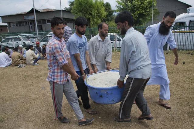 Kashmiri Muslim volunteers carry rice for distribution to the attendants of patients at Kashmir's main hospital Sher-I-Kashmir Institute of Medical Sciences on the eleventh straight day of curfew in Srinagar, Indian controlled Kashmir, Tuesday, July 19, 2016. (Photo by Dar Yasin/AP Photo)