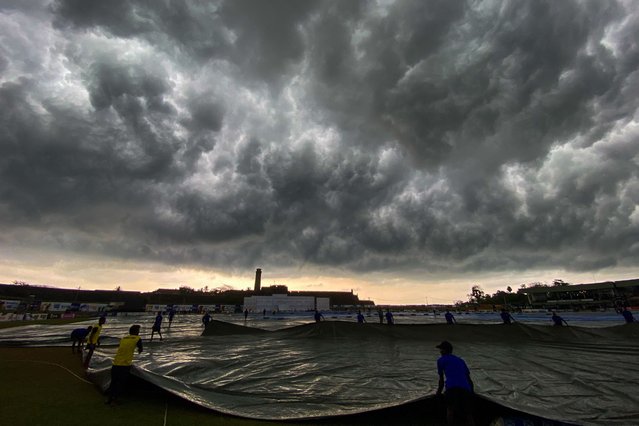 Ground staff cover the cricket pitch as the match gets delayed due to bad light during the fourth day of play of the second cricket Test match between Sri Lanka and Pakistan at the Galle International Cricket Stadium in Galle on July 27, 2022. (Photo by Ishara S. Kodikara/AFP Photo)