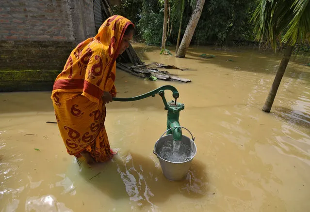 A woman fetches water from a partially submerged hand pump in a flood-affected village in Sonitpur district in the northeastern state of Assam, India, September 11, 2017. (Photo by Anuwar Hazarika/Reuters)