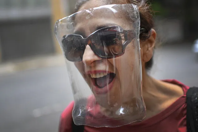 A woman wears a makeshift face shield made from a plastic bottle container as a precaution against the new coronavirus, in Caracas, Venezuela, Saturday, April 18, 2020. (Photo by Matias Delacroix/AP Photo)