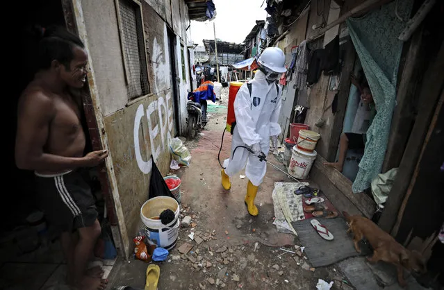 Residents watch as disinfectant is sprayed in an alleyway in an attempt to curb the spread of the coronavirus in a slum area in Jakarta, Indonesia, Wednesday, April 22, 2020. (Photo by Dita Alangkara/AP Photo)