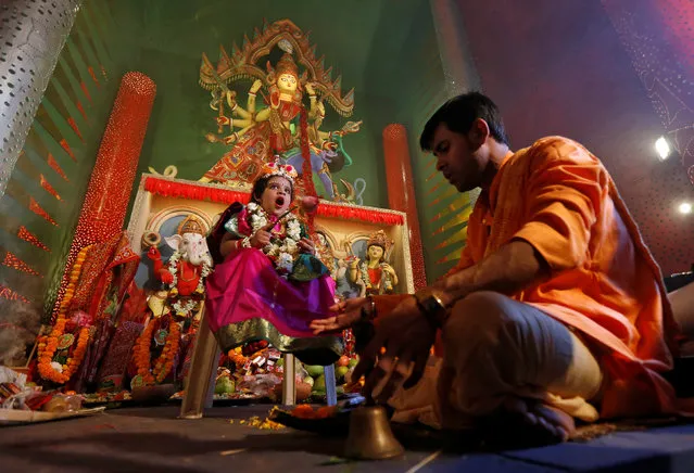 Soumili Mukherjee, a five-year old girl dressed as a Kumari, yawns as she is worshipped by a Hindu priest as a part of the Durga Puja rituals at a temporary platform called pandal during the Hindu religious festival Durga Puja in Kolkata, September 28, 2017. (Photo by Rupak De Chowdhuri/Reuters)