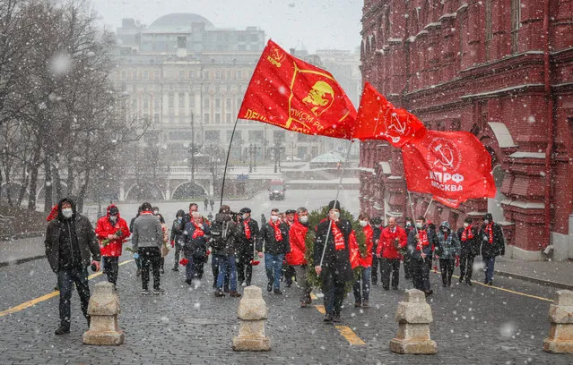 Members of the Russian Communist party hold red flags and flowers as they wait to visit Lenin's mausoleum on the Red square in Moscow, as they celebrate the 150th anniversary of his birthday, in Moscow, Russia, 22 April 2020. Vladimir Lenin, a founder of the Russian Communist party and father of the communist revolution in Russia is buried as a mummy on the central capital square. There have been demands to rebury Lenin next to his mother at Volkovo cemetery in St. Petersburg, according to what is said was his will. (Photo by Yuri Kochetkov/EPA/EFE)