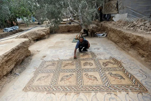 Palestinian farmer Salman al-Nabahin cleans a mosaic floor he discovered at his farm and which dates back to the Byzantine era, according to officials, in the central Gaza Strip on September 18, 2022. (Photo by Ibraheem Abu Mustafa/Reuters)