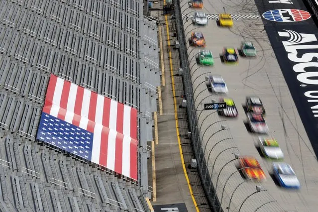 Cars speed past empty stands during a NASCAR Cup Series auto race at Bristol Motor Speedway Sunday, May 31, 2020, in Bristol, Tenn. The race is being run without fans in the stands due to the coronavirus outbreak. (Photo by Mark Humphrey/AP Photo)