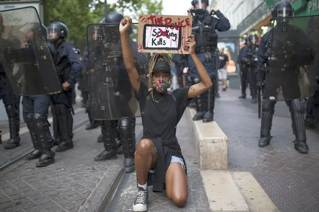 A protester kneels in front of French riot police with a sign that reads “The Police Kills” in Marseille, southern France, Saturday, June 6, 2020, to protest against the recent death of George Floyd. Floyd, a black man, died after he was restrained by police officers May 25 in Minneapolis, that has led to protests in many countries and across the U.S. Further protests are planned over the weekend in European cities, some defying restrictions imposed by authorities due to the coronavirus pandemic. (Photo by Daniel Cole/AP Photo)