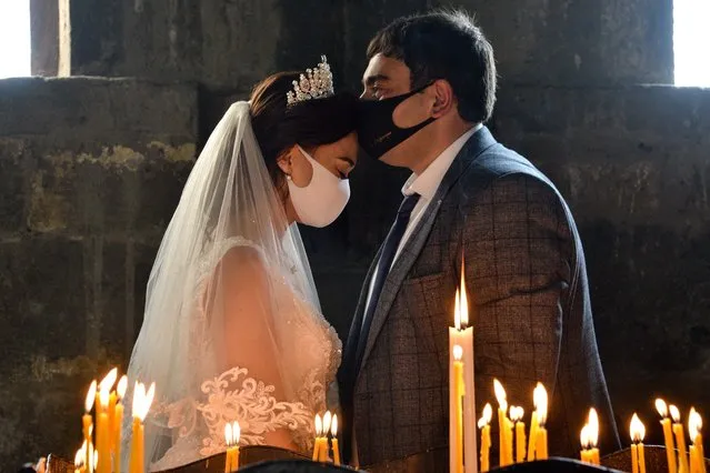 A bride and a bridegroom wearing protective face masks exchange kisses during a wedding ceremony in a church in the Saghmosavan village outside Yerevan on June 14, 2020, as the country tries to curb the spread of the COVID-19, the disease caused by the novel coronavirus. (Photo by Karen Minasyan/AFP Photo)