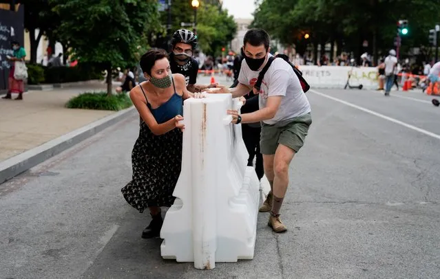 Protestors work together to push street barricades into the middle of H Street along Lafayette Park across from the White House as they move to re-block the street along Black Lives Matter Plaza after Washington Metropolitan Police officers pushed back racial inequality demonstrators to re-open the street and clear it for the resumption of vehicle traffic in Washington, D.C., U.S., June 22, 2020. (Photo by Joshua Roberts/Reuters)