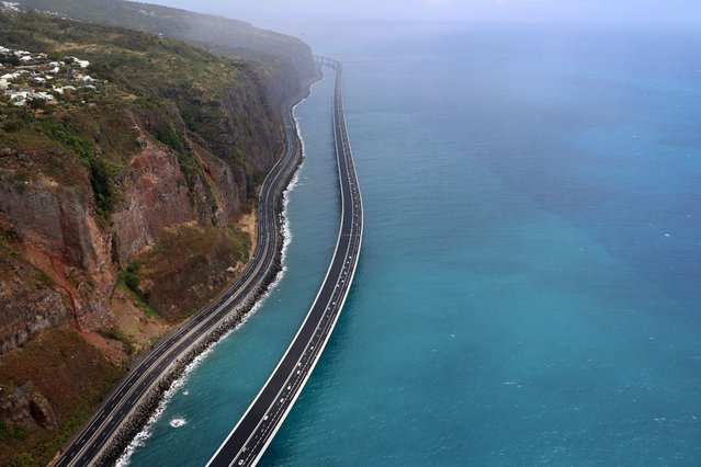 This aerial view taken on August 28, 2022, shows vehicles travelling on the “New Coastal Road” 'Nouvelle Route du Littoral (NRL)' near Saint-Denis La Reunion on the French Indian Ocean Island of Reunion, after it was partially opened – reportedly as France's most expensive road project. The coastal viaduct section forms a 5.4km-long section of the 12.5km highway which links the two main cities of Reunion Island, Saint-Denis and La Possession. (Photo by Richard Bouhet/AFP Photo)
