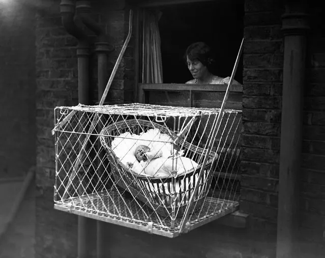 Baby in cage hung out of window, circa 20s. (Photo by Hulton-Deutsch Collection/CORBIS/Corbis via Getty Images)