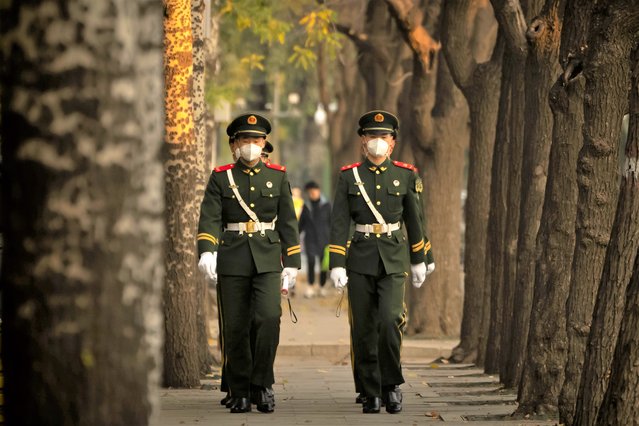 Chinese paramilitary police wearing face masks walk in formation along a street in Beijing, Thursday, November 17, 2022. (Photo by Mark Schiefelbein/AP Photo)