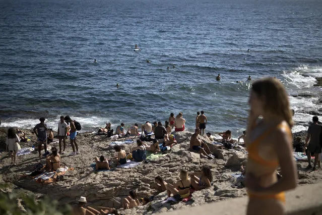 People enjoy the sun at the Malmousque Beach in Marseille, in southern France, Saturday, July 25, 2020. France is reporting a sharp uptick in coronavirus cases, with more than 1,000 new infections on Thursday, as people let their guard down heading into the country's summer break. (Photo by Daniel Cole/AP Photo)