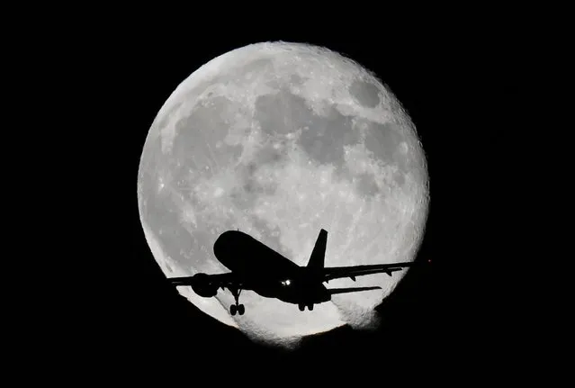 An aircraft passes in front of the moon as it makes its landing approach to Heathrow Airport in London, Britain on November 9, 2022. (Photo by Toby Melville/Reuters)