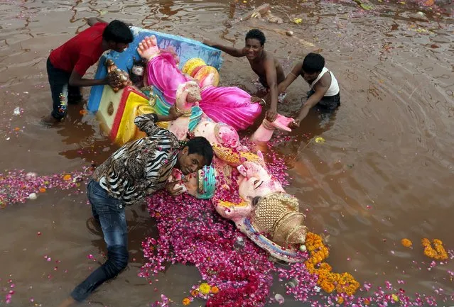 Volunteers push an idol of the Hindu god Ganesh, the deity of prosperity, as they try to remove the idol from a temporary pond after its immersion during the ten-day-long Ganesh Chaturthi festival in Ahmedabad, India, September 22, 2015. (Photo by Amit Dave/Reuters)