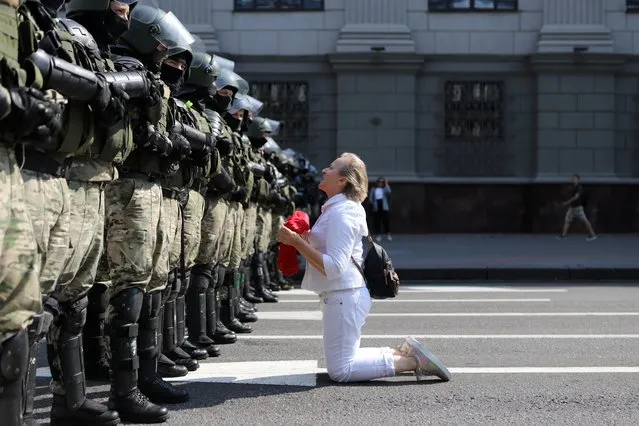 A woman kneels in front of a riot police line as they block Belarusian opposition supporters rally in the center of Minsk, Belarus, Sunday, August 30, 2020. Opposition supporters whose protests have convulsed the country for two weeks aim to hold a march in the capital of Belarus. (Photo by AP Photo/Stringer)