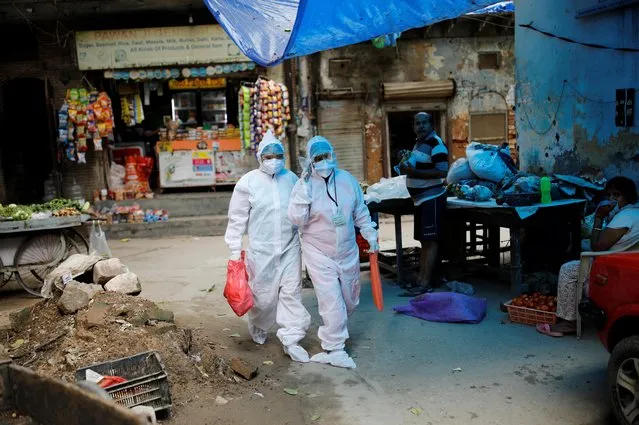 Health worker Kamal Kumari and her assistant walk as they deliver pulse oximeters to people infected with the coronavirus in New Delhi, India, August 26, 2020. (Photo by Adnan Abidi/Reuters)