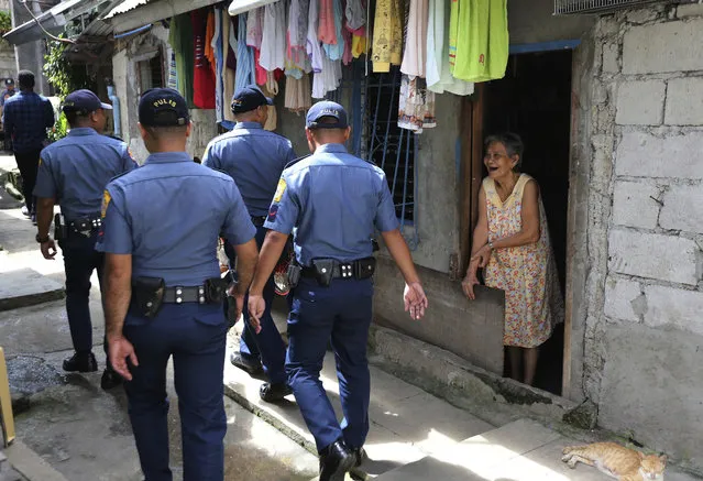 An elderly woman smiles as policemen walk past her house as they conduct a visit to homes at a poor community as part of a government anti-drug crackdown in metropolitan Manila, Philippines, Monday, January 29, 2018. The Philippine police chief said his force will resume visits to the homes of drug suspects to encourage them to reform, despite his acknowledgement that corrupt police have abused the program. (Photo by Aaron Favila/AP Photo)