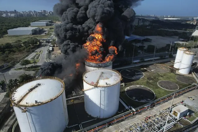 A gasoline storage container burns at Bravo Petroleum in Barranquilla, Colombia, Wednesday, December 21, 2022. A firefighter died while trying to put out the fire, according to local authorities. (Photo by Jose Torres/AP Photo)