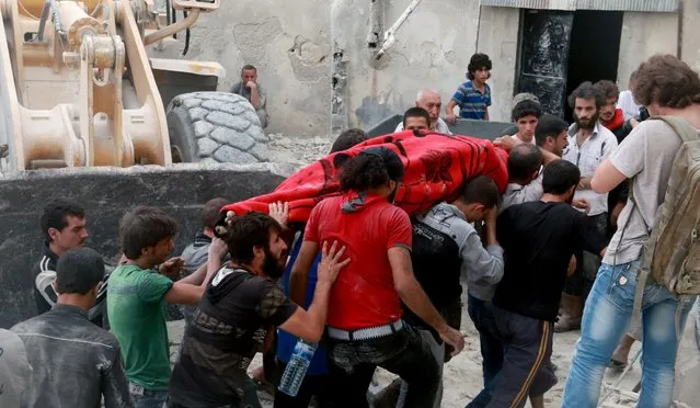 Search and rescue team members carry a dead body from debris of a building after warcrafts belonging to Syrian and Russian army carried out an airstrike on opposition controlled residential area at Merce neighborhood of Aleppo, Syria on September 23, 2016. (Photo by Jawad al Rifai/Anadolu Agency/Getty Images)