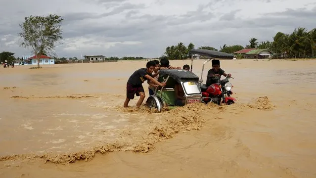 Residents push a tricycle along a flooded highway in Sta Rosa, Nueva Ecija in northern Philippines, October 19, 2015, after it was hit by Typhoon Koppu. (Photo by Erik De Castro/Reuters)