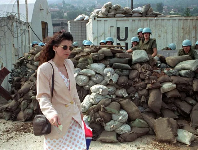 In this Saturday July 29, 1995 file photo, a Sarajevan woman walks past French United Nations soldiers preparing new barricades at a U.N. compound in Sarajevo, on a relatively peaceful day in the beseiged Bosnian capital. (Photo by Karsten Thielker/AP Photo/File)
