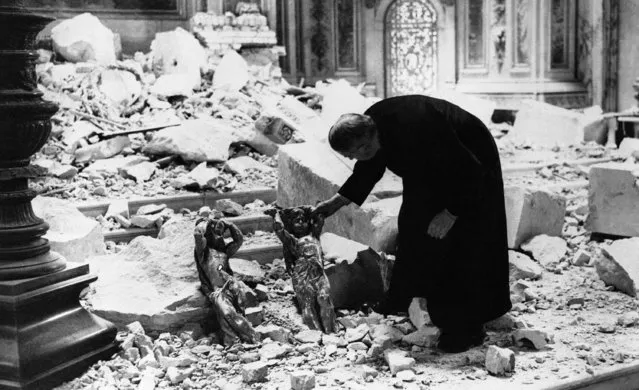 One of the clergy of St. Paul's cathedral in London looks at two cherubs standing among the debris and holding their heads as though for protection, October 10, 1940 in London. The destruction was caused by a bomb. (Photo by AP Photo)