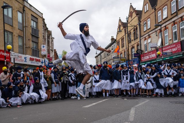 A Sikh devotee demonstrates sword fighting techniques during the Nagar Kirtan procession on April 7, 2024 in Southall, England. The Nagar Kirtan procession takes place during the festival of Vaisakhi which celebrates the spring harvest, primarily in Punjab and Northern India. Traditionally, Nagar Kirtan is led by the Panj Piare (the five beloved of the Guru), who are followed by the Sikh holy scripture, which is placed on a float. Participants in the procession are often shoeless in deference to the displayed scripture while the road before the procession is cleared by Sewadars. (Photo by Carl Court/Getty Images)