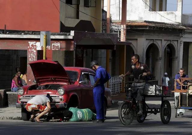 Cubans repair a car on a street in Havana October 27, 2015. (Photo by Enrique De La Osa/Reuters)