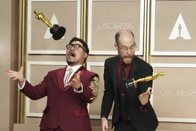 Film directors Daniel Kwan, left, and Daniel Scheinert toss their awards for best picture for “Everything Everywhere All at Once” as they pose in the press room at the Oscars on Sunday, March 12, 2023, at the Dolby Theatre in Los Angeles. (Photo by Jordan Strauss/Invision/AP Photo)