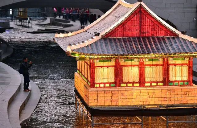 A man takes pictures of colorful lanterns in the shape of a Korean royal palace on the eve of the Seoul Lantern Festival at  Cheonggyecheon stream in central Seoul on November 5, 2015. The festival is part of a campaign by South Korea to attract more foreign tourists, which runs from November 6 to 22. (Photo by Jung Yeon-Je/AFP Photo)