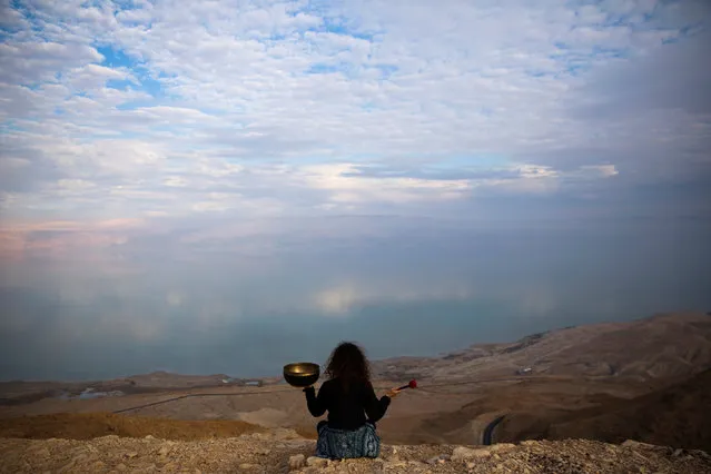 Jade holds a Tibetan singing bowl as she sits on a cliff overlooking the Dead Sea, near Metzoke Dragot in the Israeli occupied West Bank, February 20, 2018. (Photo by Ronen Zvulun/Reuters)