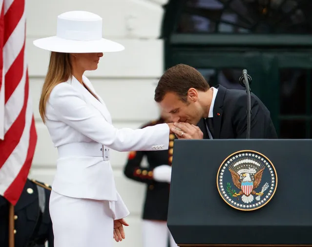 Brigitte Macron, left, and President Donald Trump, right, look on as French President Emmanuel Macron kisses the hand of first lady Melania Trump during a State Arrival Ceremony on the South Lawn of the White House, Tuesday, April 24, 2018, in Washington. (Photo by Evan Vucci/AP Photo)