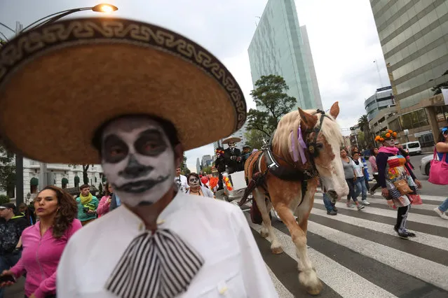 People with their faces painted to look like the popular Mexican figure called “Catrina” and others painted as skulls take part in a procession to celebrate the upcoming annual Day of the Dead on November 1 and 2, at Reforma avenue, in Mexico City, Mexico, October 23, 2016. (Photo by Edgard Garrido/Reuters)