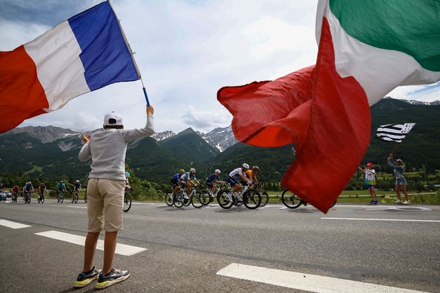 The The lead breakaway cycles past spectators waving a French and an Italian flag, in the French Alps during the 4th stage of the 111th edition of the Tour de France cycling race, 140 km between Pinerolo in Italy, and Valloire in France, on July 2, 2024. (Photo by Anne-Christine Poujoulat/AFP Photo)