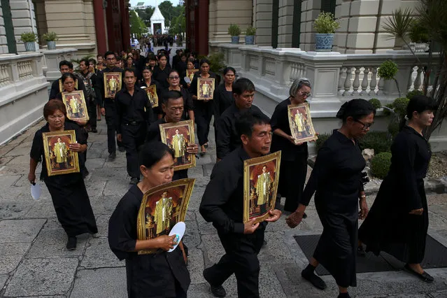 Mourners hold up pictures of Thailand's late King Bhumibol Adulayadej as they walk in line into the Throne Hall at the Grand Palace for the first time to pay respects to his body that is kept in a golden urn in Bangkok, Thailand, October 29, 2016. (Photo by Athit Perawongmetha/Reuters)