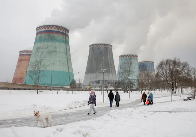 People walk in a park near chimneys of a heating power plant on a cold winter day in Moscow, Russia on January 12, 2021. (Photo by Maxim Shemetov/Reuters)