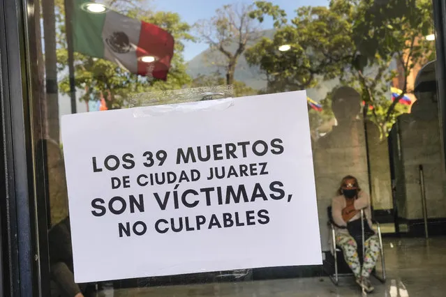 A sign with a message that reads in Spanish: “The 39 dead in Ciudad Juarez are victims, not culprits”, is taped to a glass door of the Mexican embassy in Caracas, Venezuela, Wednesday, March 29, 2023. Immigration authorities identified the dead and injured as being from Guatemala, Honduras, El Salvador, Venezuela, Colombia and Ecuador. (Photo by Matias Delacroix/AP Photo)