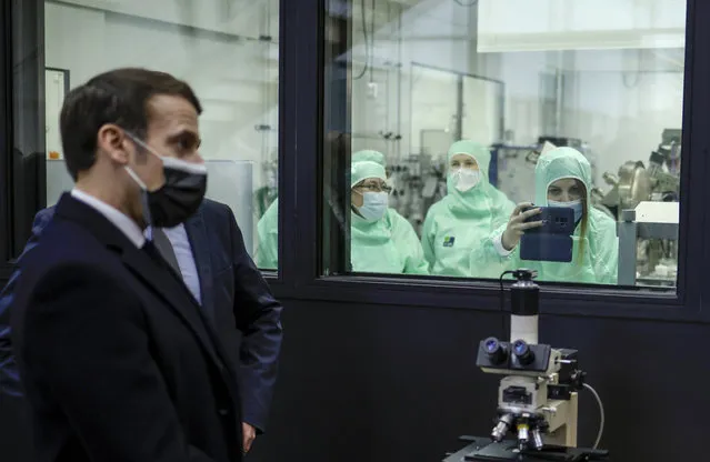 A researcher takes a photograph with a mobile phone as French President Emmanuel Macron as he pays a visit to the Centre de Nanosciences et de Nanotechnologies (C2N) of the French National Center for Scientific Research (CNRS) at the Paris-Saclay University research unit in Orsay, near Paris on January 21, 2021, where he will present the French quantum strategy. (Photo by Yoan Valat/Pool via AFP Photo)