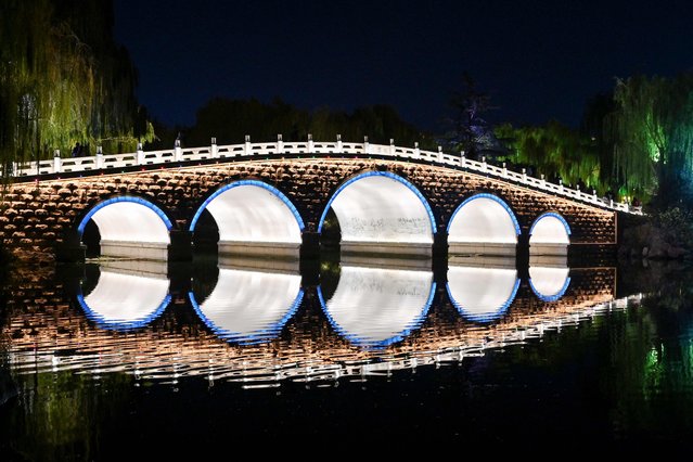 Visitors walk across an illuminated bridge at the Daming Lake Park in Jinan, China's eastern province of Shandong on December 8, 2024. (Photo by Adek Berry/AFP Photo)