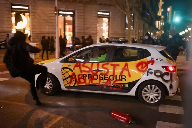 A car with a graffiti on it drives amidst a protest in support of Pablo Hasel in Barcelona, Spain, February 16, 2021. Hasel was convicted over lyrics and tweets that included references to the Basque separatist paramilitary group ETA, compared Spanish judges to Nazis and called former king Juan Carlos a mafia boss. (Photo by Nacho Doce/Reuters)